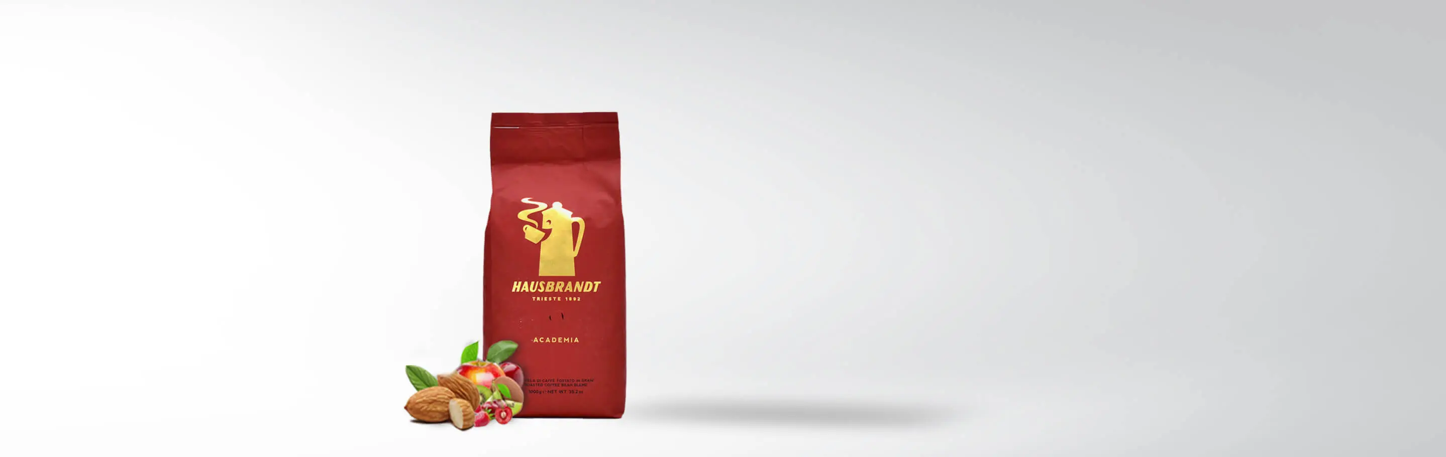 A pack of Hausbrandt Academia coffee beans next to nuts and fruits on a white background