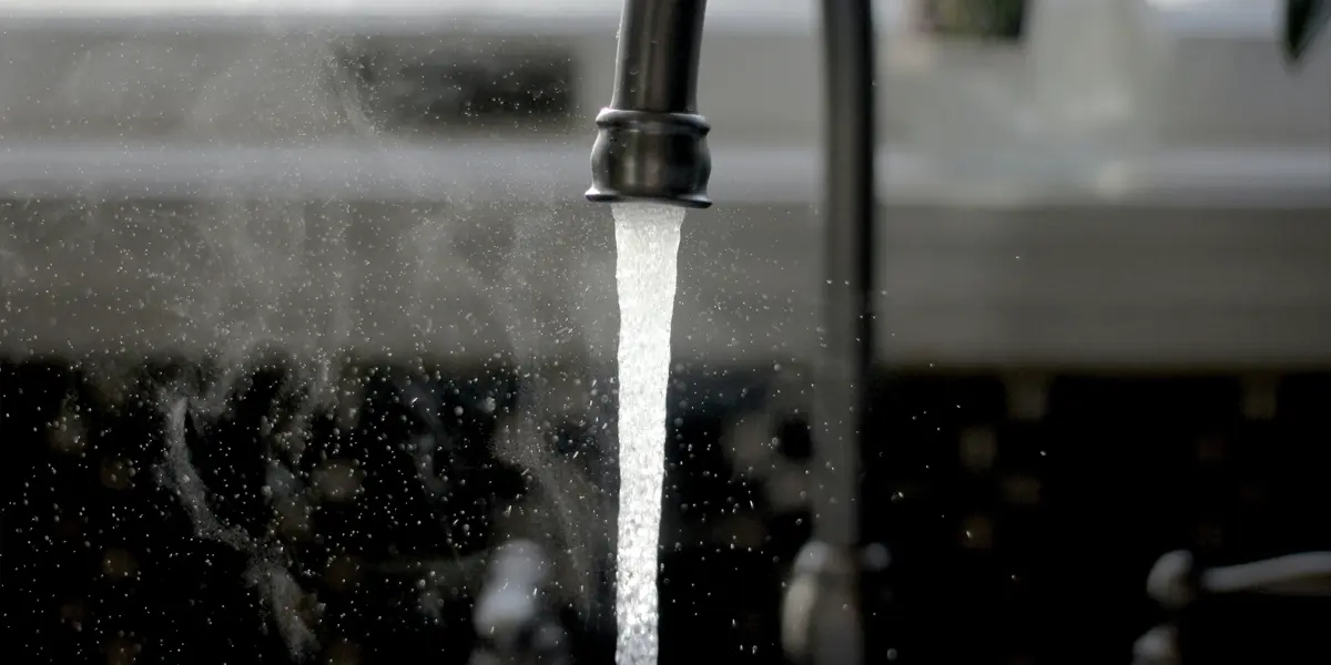 Nahaufnahme eines Küchenhahns, aus dem Wasser fließt