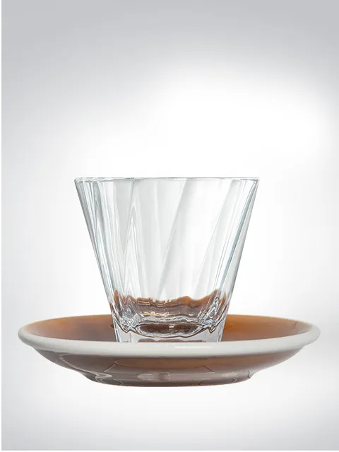 A transparent glass with a brown saucer