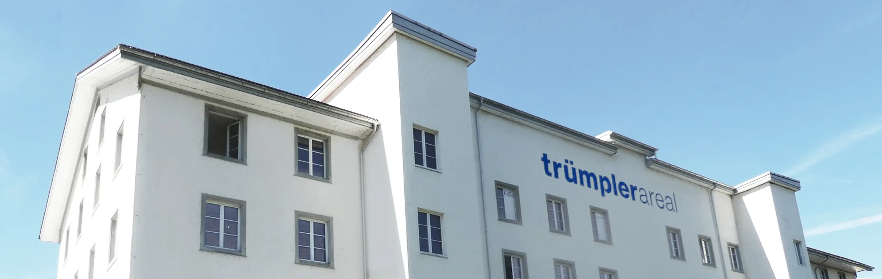 Photo of a white building with the inscription Trümplerareal
