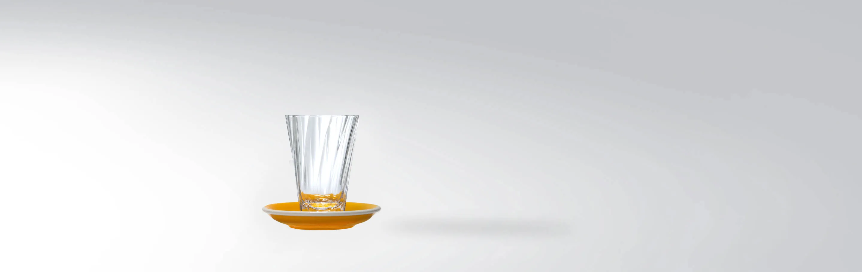 Un verre élégant avec une soucoupe jaune assortie sur un fond neutre.