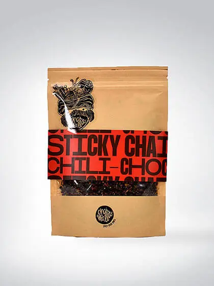 Verpackung von Sticky Chai Chili-Choco mit rotem Etikett, Teemischung mit einer Kombination aus Schokolade und Gewürzen, abgebildet vor weißem Hintergrund