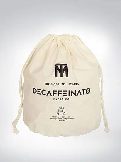 Beiger Baumwollbeutel mit Aufschrift 'Tropical Mountains Decaffeinato Pacifico', enthält 100 biologisch abbaubare Kaffeekapseln.