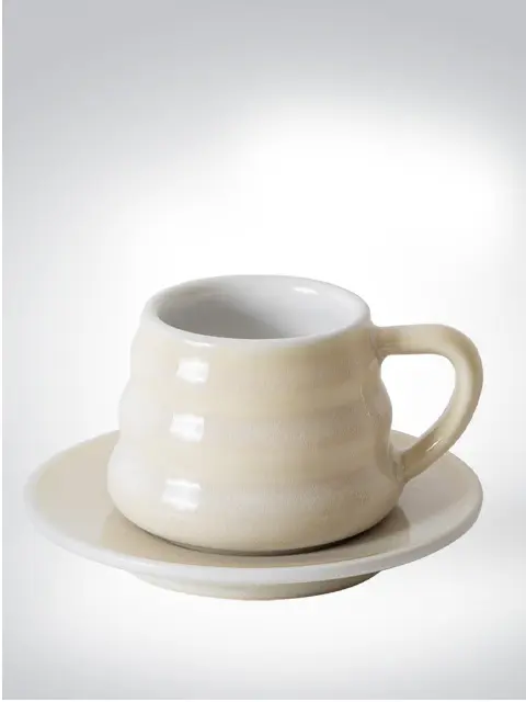 Stylish beige coffee mug on matching saucer