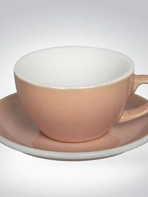 Pastellrosa Keramiktasse mit passender Untertasse, perfekt für Kaffeespezialitäten.