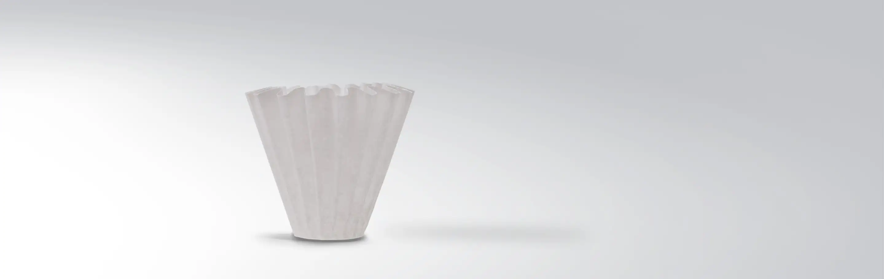 Single white paper coffee filter against grey background